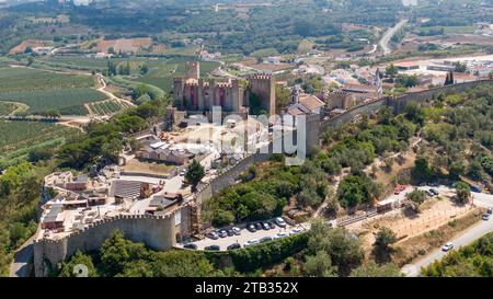 Vista aerea del castello di Óbidos e delle mura medievali che circondano il villaggio storico nel Portogallo centrale, il paesaggio fortificato della città in cima alla collina. Agosto 2022 Foto Stock