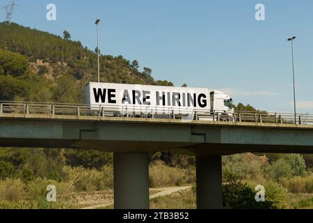 Un veicolo sta attraversando il ponte, con l'iscrizione sul rimorchio - STIAMO NOLEGGIANDO. Concetto di logistica. Foto Stock