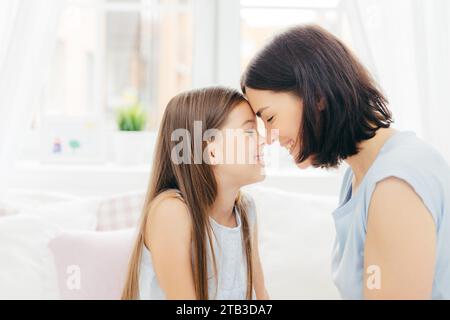 Affettuose madre e figlia toccano il naso in un momento delicato Foto Stock