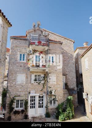 Budva, Montenegro - 08 agosto 2023: Vecchia casa in pietra con ghirlande di piante verdi sui balconi Foto Stock