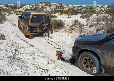 Veicolo a quattro ruote motrici che traina SUV 4X4 sulla sabbia sciolta durante la guida fuoristrada lungo la costa occidentale malgascia, regione di Atsimo-Andrefana, Madagascar Foto Stock