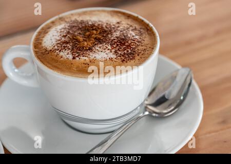 Immagine ravvicinata di un caffè cappuccino ricoperto di cioccolato in polvere. Foto Stock