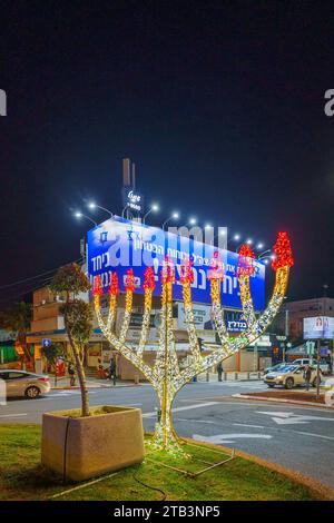 Haifa, Israele - 02 dicembre 2023: Mostra Hannukah menorah, con segno di unità di guerra sullo sfondo, Haifa, Israele Foto Stock