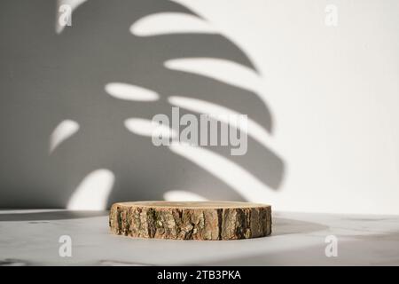 Podio in legno con ombra di foglie monstera per la presentazione di cosmetici naturali o prodotti Foto Stock