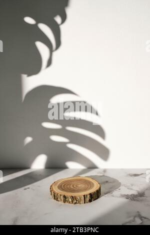 Podio in legno con ombra di foglie monstera per la presentazione di cosmetici naturali o prodotti Foto Stock