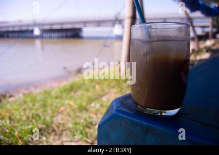 shot su vetro riempito con ghiaccio al cioccolato con fondo marino e ponte Foto Stock