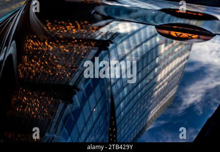 Un London Black Cab in attesa di un cliente presso lo Shard in Thomas Street. L'immagine mostra il riflesso. Del cartello giallo del taxi in una foto creativa. Foto Stock