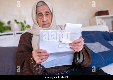 la vecchia che ha in mano i costi di controllo delle ricevute della vita e dell'affitto della casa e i suoi debiti Foto Stock