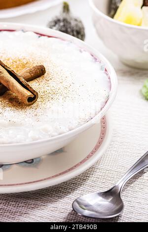 ciotola per budino di riso, budino fatto in casa a base di riso macinato, addolcito con polvere di cannella e corteccia di cannella. Dolci brasiliani rurali in background, Foto Stock