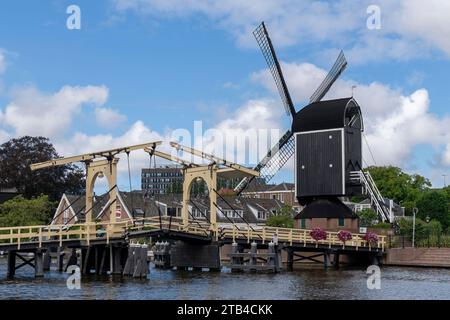 Storico mulino a vento De Put e ponte Rembrandt sul fiume Rijn nella città di Leida, nei Paesi Bassi, contro un cielo blu nuvoloso e bianco Foto Stock