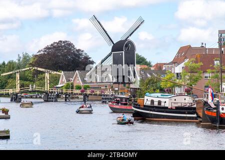 Leida, Paesi Bassi - 15 agosto 2023; vista sul fiume Rijn affollata di barche e storico mulino a vento De Put e ponte Rembrandt Foto Stock