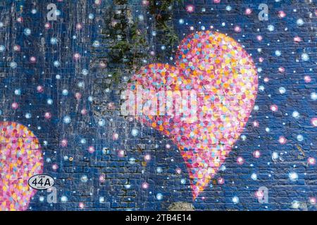 Graffiti su un muro di mattoni con un udito multicolore con sfondo blu Foto Stock