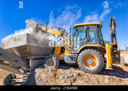 escavatore con terna che carica un rimorchio con cemento Foto Stock