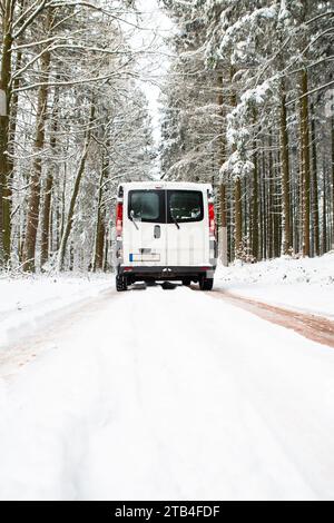 Camper Van guida su una strada attraverso una foresta coperta di neve in inverno, vacanza avventura e stile di vita nei boschi, Germania Foto Stock