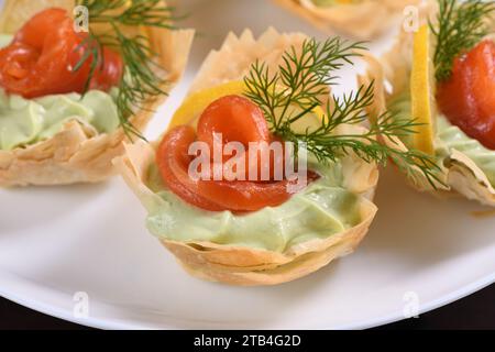 Avocado montato con crema di formaggio soffice nella mousse più delicata, una fetta di salmone e limone. Servita in cesti croccanti con pasta phyllo cotta al forno Foto Stock