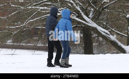 Ein Paar geht auf einem mit Schnee bedecktem Weg im Stadtpark Hamburg entlang. Winterhude Amburgo *** Un paio di passeggiate lungo un sentiero innevato nel Parco cittadino di Amburgo Winterhude Hamburg Credit: Imago/Alamy Live News Foto Stock