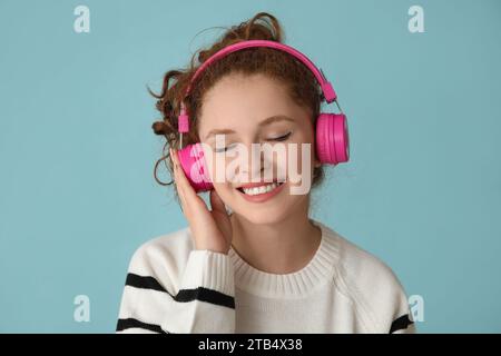Ritratto di una giovane donna rilassata che ascolta musica su sfondo blu Foto Stock