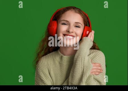 Ritratto di una giovane donna rilassata che ascolta musica su sfondo verde Foto Stock