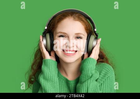 Ritratto di una giovane donna rilassata che ascolta musica su sfondo verde Foto Stock