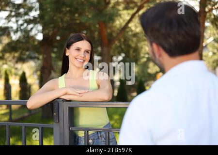 Rapporto amichevole con i vicini. Donna e uomo felici vicino alla recinzione all'aperto Foto Stock