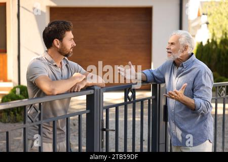 Vicini emotivi che discutono vicino alla recinzione all'aperto Foto Stock