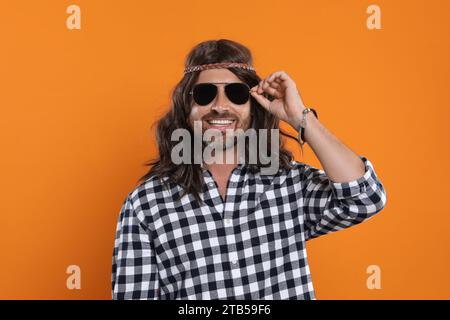 Uomo hippie con occhiali da sole su sfondo arancione Foto Stock