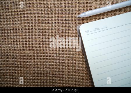 Quaderno scolastico a spirale bianco e nero su sfondo burlap con spazio per la copia del testo Foto Stock