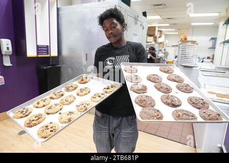 University City, Stati Uniti. 8 dicembre 2023. Il manager Trevion Henderson porta i biscotti freschi nella vetrina dell'Insomnia Cookies in occasione del National Cookie Day a University City, Missouri, lunedì 4 dicembre 2023. Foto di Bill Greenblatt/UPI credito: UPI/Alamy Live News Foto Stock