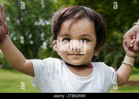 Ritratto di un bambino felice e carino che gioca con mamma e papà e che si divertono nel parco all'aperto. Foto Stock