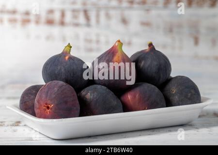 Fichi freschi confezionati su fondo di legno bianco. Prodotti agricoli biologici Foto Stock