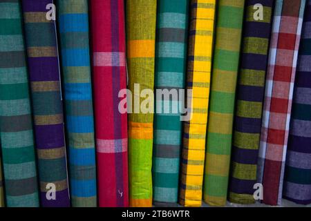 Gli uomini tradizionali bengalesi multicolori indossano lungi ripiegati su un rack in un negozio. Può essere utilizzato come sfondo con texture pattern Foto Stock