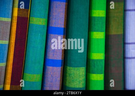 Gli uomini tradizionali bengalesi multicolori indossano lungi ripiegati su un rack in un negozio. Può essere utilizzato come sfondo con texture pattern Foto Stock