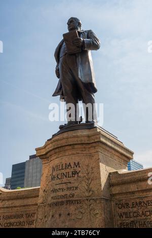 Vista dal basso, una statua di bronzo di un uomo in piedi sormonta un piedistallo di pietra con l'iscrizione William McKinley vicino al Campidoglio dell'Ohio a Columbus, Ohio. Foto Stock