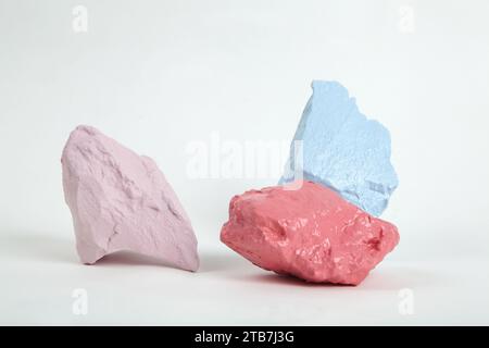 3 colorare pietre o ciottoli in tonalità di rosa, salmone e blu pastello isolate su uno sfondo bianco. Fermi immagine minimi e fotografie vivaci Foto Stock