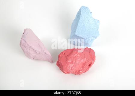 3 colorare pietre o ciottoli in tonalità di rosa, salmone e blu pastello isolate su uno sfondo bianco. Fermi immagine minimi e fotografie vivaci Foto Stock