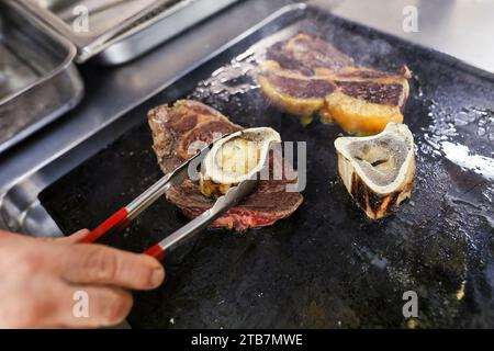 Preparazione di una bistecca di costolette “entrecote Bordelaise” (bistecca alla Bordeaux), Bazas beef. Cottura della carne, carne rara e marrowbone Foto Stock