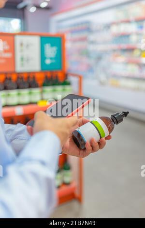 Mani tagliate di un senior anonimo che utilizza un'app sul telefono cellulare per controllare le informazioni sul prodotto prescritto in farmacia Foto Stock