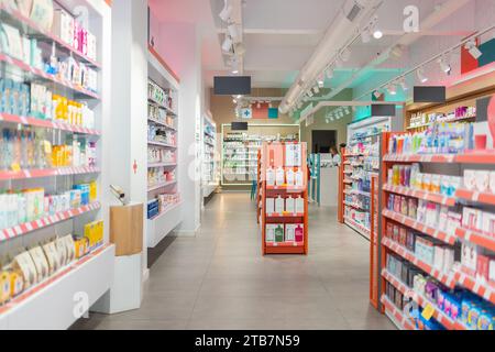Farmaci assortiti esposti e disposti su più ripiani e navate vuote in un moderno negozio farmaceutico Foto Stock