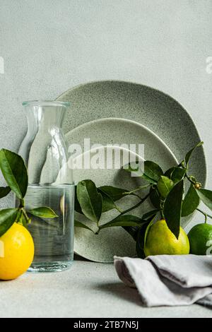 Un sofisticato ambiente da tavola con raffinati piatti in ceramica, limoni freschi e pere su uno sfondo di lino testurizzato. Foto Stock