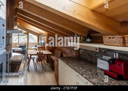 Un caldo e invitante abitacolo in legno caratterizzato da una moderna cucina con elettrodomestici in acciaio inox, ripiani in granito e una spaziosa area pranzo Foto Stock