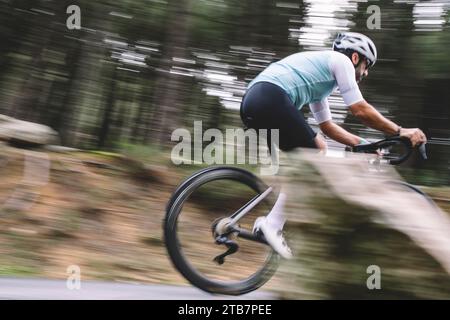 Foto d'azione di un ciclista in movimento sfocata che corre in discesa su una strada forestale Foto Stock