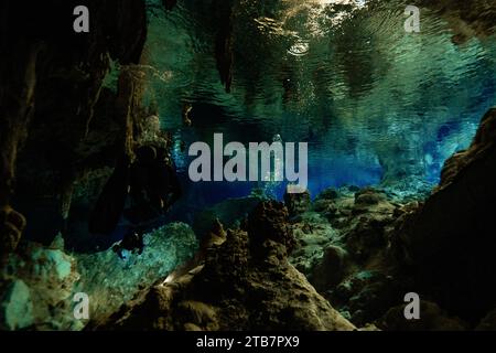 Anonimo subacqueo immerso nel paesaggio mozzafiato sottomarino di Cenote Dos Ojos, in Messico, mentre nuota nelle tranquille acque blu che m Foto Stock