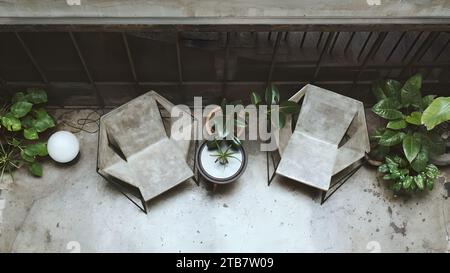 Vista dall'alto dell'elegante soggiorno con 2 sedie. Interni in colori grezzi nero e grigio con elementi di albero decorato e granito scuro. Foto Stock