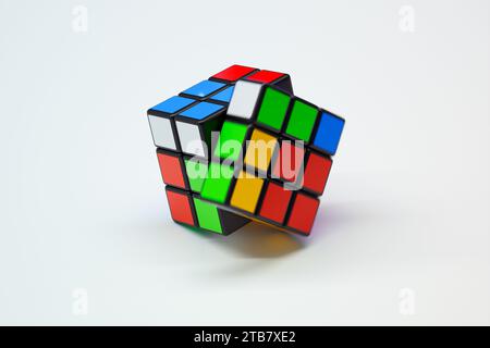 Questa immagine mostra un cubo di Rubik complesso e risolto posizionato su uno sfondo bianco, enfatizzando i quadrati e gli iconi dai colori vivaci del cubo Foto Stock