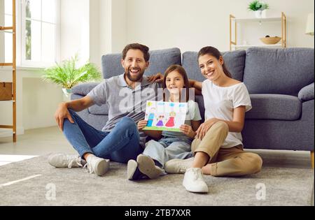 Madre, padre e figlia felici che si divertono e disegnano ritratti di famiglia insieme Foto Stock