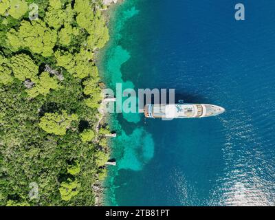 Annidato nell'abbraccio azzurro del Mar Egeo, questo yacht rappresenta l'epitome della tranquillità, ancorato al largo della costa panoramica della Croazia. Foto Stock