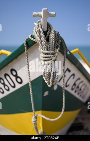 Yport, Francia - 21 luglio 2022: La parte anteriore di un piccolo peschereccio bianco verde che giace sulla spiaggia di Yport, giorno di sole in estate, corda Foto Stock