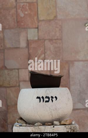 Un cartello di pietra che regge il casco di un vecchio soldato è inciso con la parola ebraica "ricorda" sul terreno del Monte Cimitero militare di Herzl a Je Foto Stock