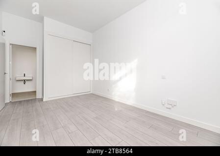 Camera da letto in una casa in stile loft con guardaroba bianco incassato con porte scorrevoli, Foto Stock