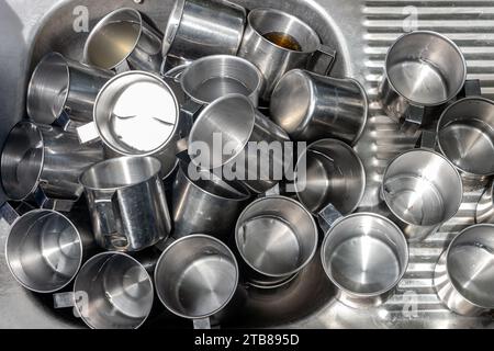 Un mucchio di tazze in alluminio nel lavandino Foto Stock
